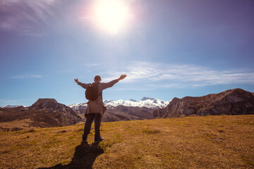 A man with hands in the air on the top of mount looks at beautiful panorama of the mountains. National Park Peaks of Europe. Cantabria, Spain, Europe