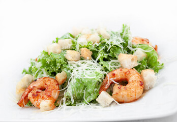 Caesar salad with shrimp close-up on a white background