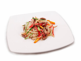 Rice noodles with fried pieces of beef and vegetables on a white plate