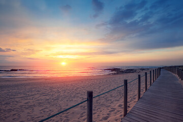 Wooden walkway on the sandy beach at magical sunset light. Beautiful seascape in the evening