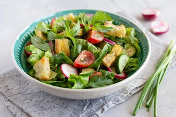 Fattoush salad with lettuce, herbs, tomatoes, cucumber, red onion, radish and pieces of toasted pita bread. Middle Eastern cuisine.