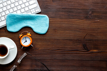 Hard exhausing work concept. Sleep mask on wooden office desk top view copyspace