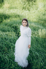 beautiful woman in long white dress posing in the field 