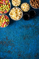 Set of flavored popcorn and soda on blue table top view copy space