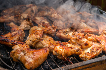 A lot of tasty, delicious, savoury meet (chicken wings) with pleasant odor and meat haze on the grill in the village