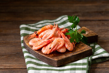 Shrimp on a wooden Board on a brown wooden table. Lots of prawns on the serving Board. Prawns close up	