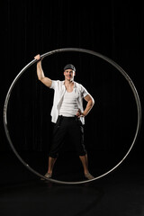 Man in circle. Circus performer artist in a Cyr Wheel (Roy Cyr) in theatre at a black background