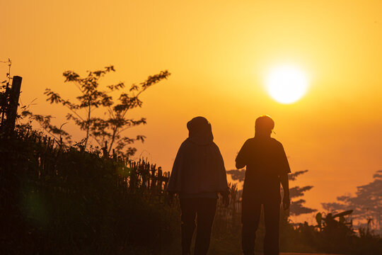 Indonesian couple silhouette walking in the middle of rice fields in the sunrise.