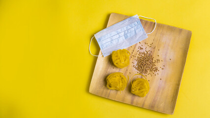 Buckwheat and pasta, medical mask in wooden plates. Slow carbs with copy space. Italian and Russian cuisine. food delivery in self-isolation. staying at home, we take care of our health. prevention