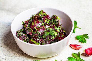 Beetroot salad with garlic and herbs in a gray bowl on white background.
