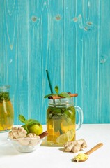 Homemade lemonade for improving metabolism with lime, mint and ginger, in a glass Cup on an aquamarine background, space