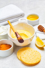 Preparation of turmeric face mask with honey and yogurt in white bowl. Skincare concept.