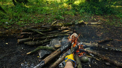 Obraz premium Cooking banger (sujuk) on campfire in forest, Camping in nature