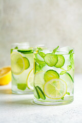 Detox sassy water with cucumber and lemon in glass, light background. Healthy eating concept.
