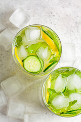 Detox sassy water with cucumber and lemon in glass, light background, top view. Healthy eating concept.
