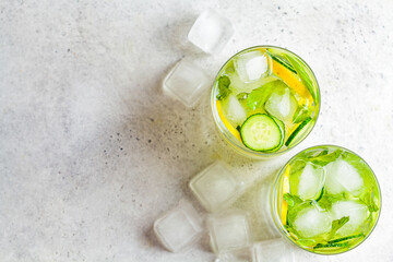 Detox sassy water with cucumber and lemon in glass, light background, top view. Healthy eating concept.