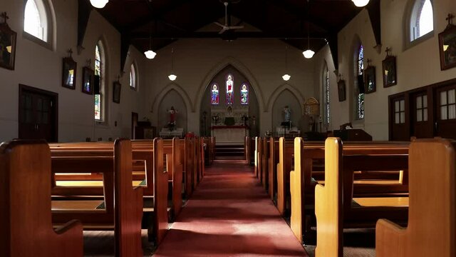 Empty church with wooden pews, facing down aisle to pulpit