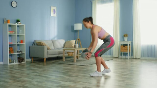 Young fit woman enters a room and spreads fitness mat, is going to practice workout at home, in good mood, is maintaining a healthy lifestyle, slow motion.