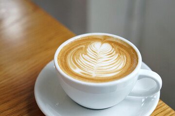 Hot Latte - A cup of coffee with milk and beautiful leaf pattern latte art on wooden table and copy space, Perfect for breakfast time.