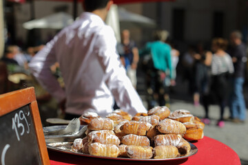  Pastry in focus on a tray near restaurant  on the street, people are blurred