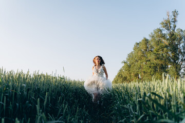 attractive woman wearing veil and long white dress standing in the field