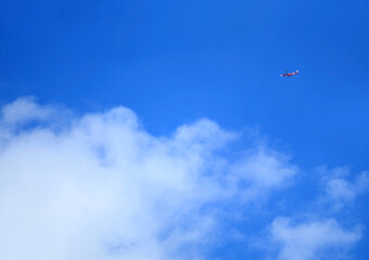 Vivid blue sky with flying jet plane and white clouds for the concept of travel or journey