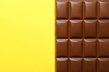 Tasty chocolate bar on yellow background. Sweet food