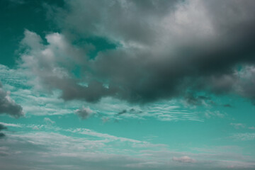 Emerald sky with white clouds on the horizon and a small rain cloud in the foreground