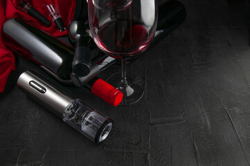 Gray electric corkscrew made of metal. Lies on a dark concrete background. Nearby are three bottles...