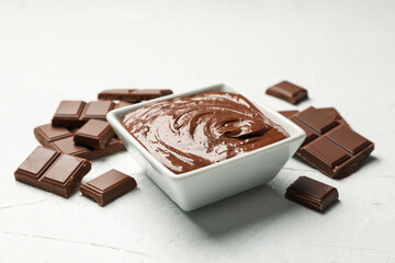 Bowl with chocolate and chocolate pieces on white background