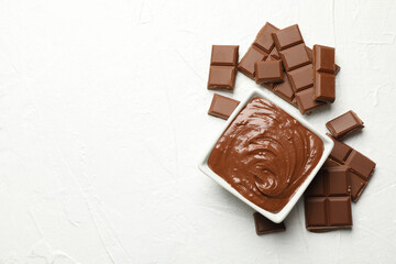 Bowl with chocolate and chocolate pieces on white background