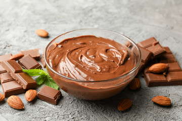 Bowl with chocolate and chocolate pieces on gray background