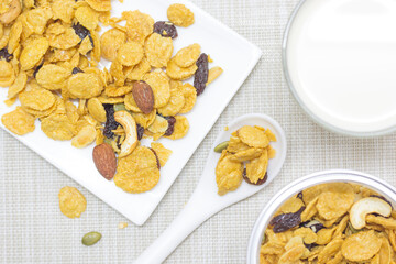Breakfast cornflakes from a can onto a white plate with fresh milk in a glass.