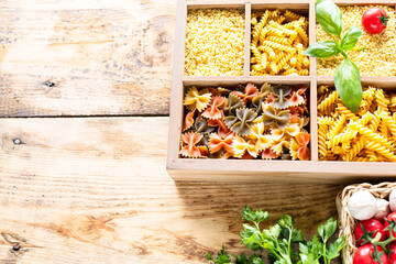 Different types of italian uncooked pasta in wooden box, whole wheat pasta, pasta, spaghetti, noodles, tagliatelle. Top view