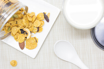 Breakfast cornflakes from a can onto a white plate with fresh milk in a glass.