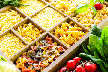 Different types of italian uncooked pasta in wooden box, whole wheat pasta, pasta, spaghetti, noodles, tagliatelle. Top view