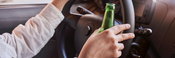 An unrecognizable female drinking beer while driving car. Concepts of driving under the influence,...
