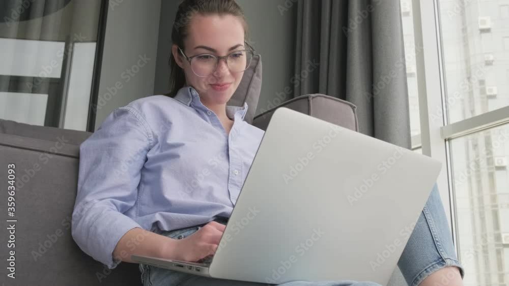 Canvas Prints view from below of satisfied attractive brunette woman in eyeglasses using laptop computer while sit