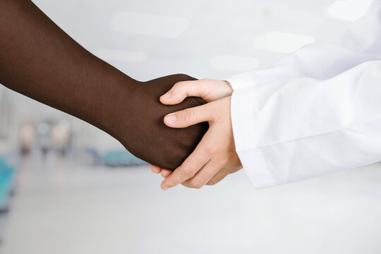 Doctor's hands holding patient's hand for encouragement and empathy. Partnership, trust and medical ethics concept.black lives matter