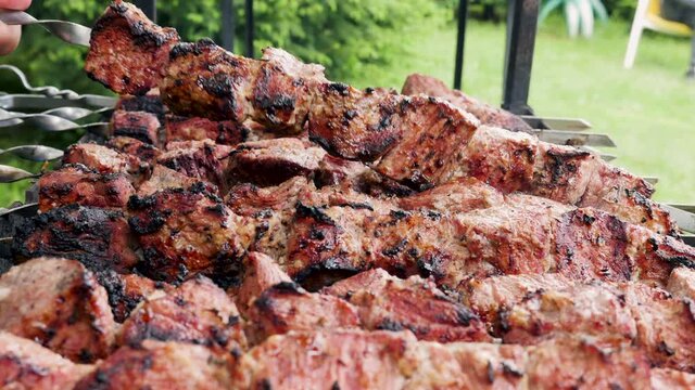 Cook fries pieces of beef meat on bbq grill with fire in open air. Traditional national marinated dish Shashlik or shish kebab is fried on barbecue. Food and Catering.
