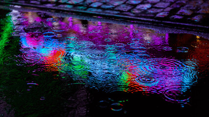 Neonlicht als Reflexion in Wasser einer Pfütze bei Regen