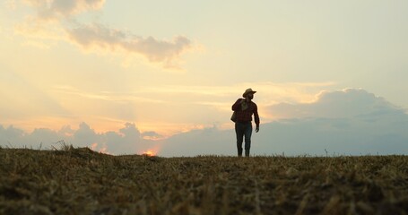 Fototapeta premium Caucasian farmer carrying a sack full of grain through the field while gathering harvest.