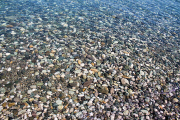Sea stones in sea water. Pebbles under water. The view from the top. Nautical background. Clean sea water. Transparent sea