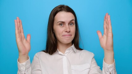 Surprised young woman isolated on blue studio background showing big size gesture with hands, attractive amazed female, impressed girl with open mouth demonstrate something wide, wears white shirt