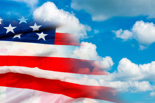 Close up image of big US flag blue sky white clouds background.