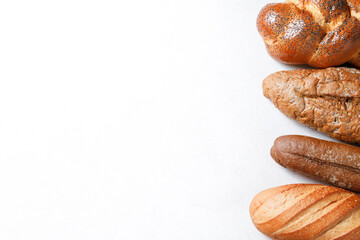 Variety of loaves of bread and buns on white background
