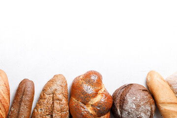 Variety of loaves of bread and buns on white background