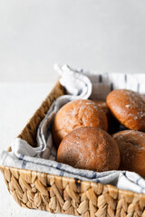 Fresh baked buns in wicker basket on bright background