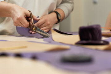 Workplace of seamstress. Dressmaker cuts textile on the sketch lines. female hand with the scissors cutting fabric.