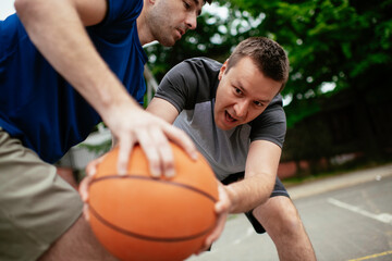 Two young men playing basketball in the park. Friends having a friendly match outdoors	